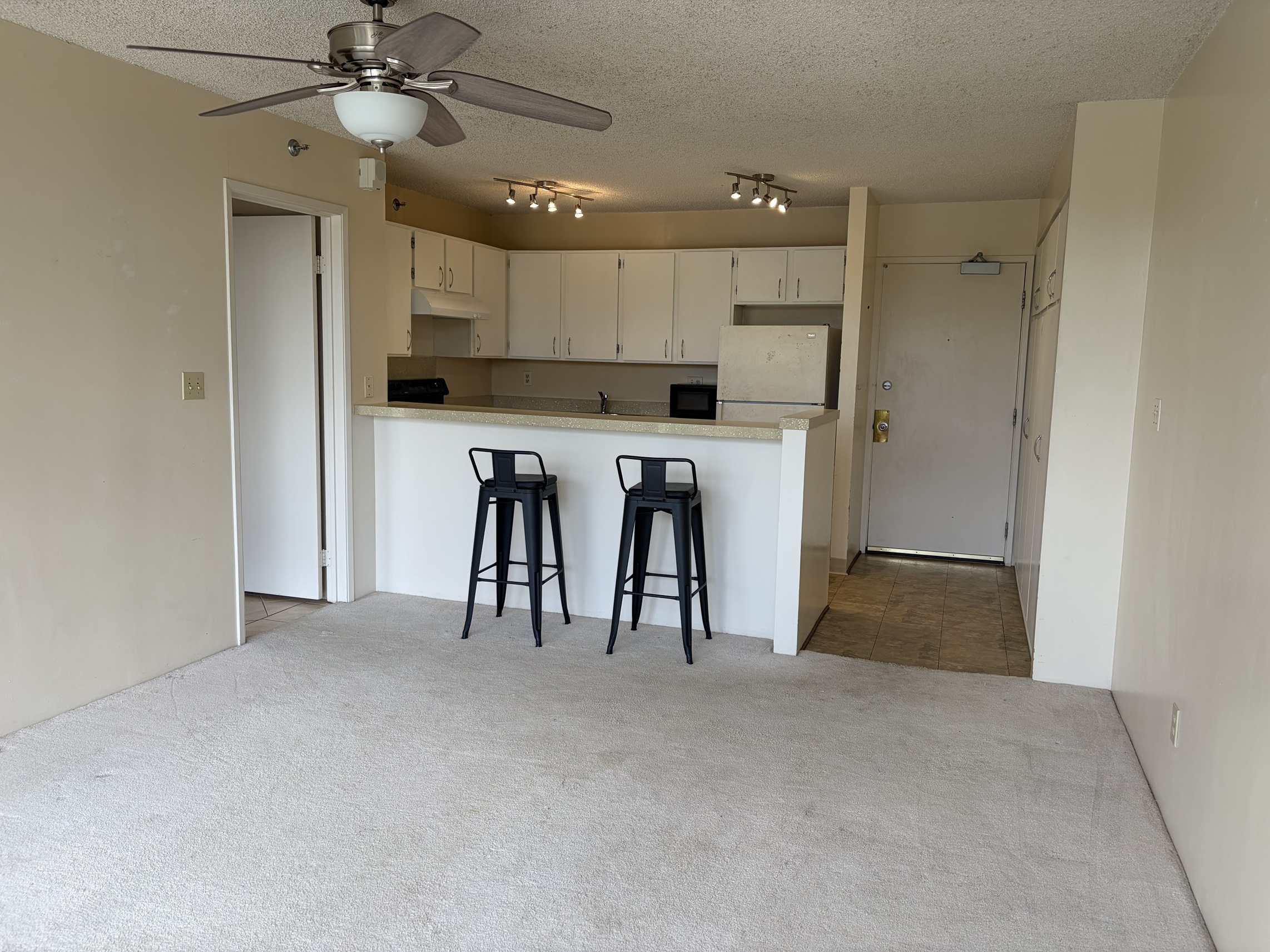 A room with a ceiling fan and two bar stools.